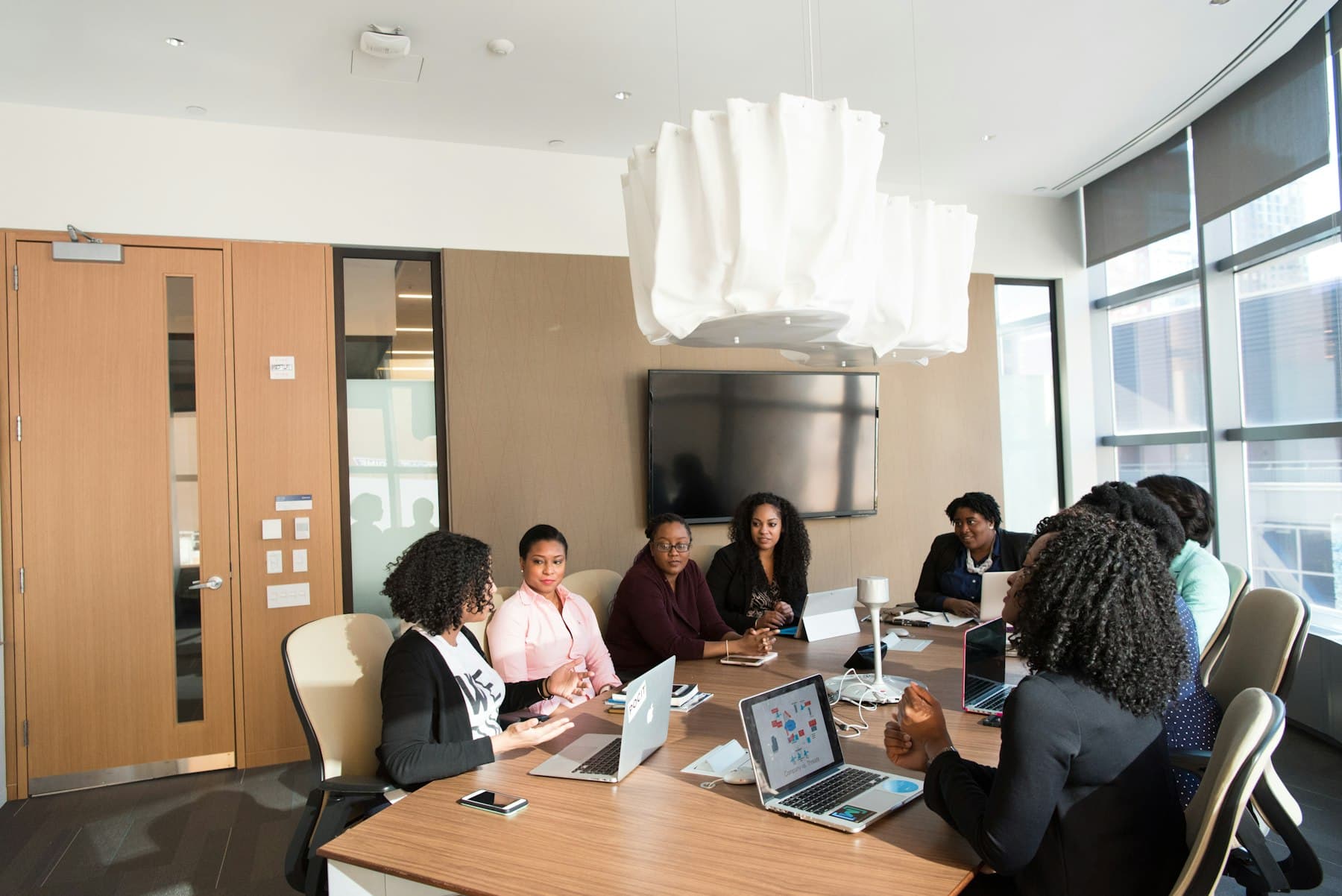 A team in discussion around a meeting table with laptops.